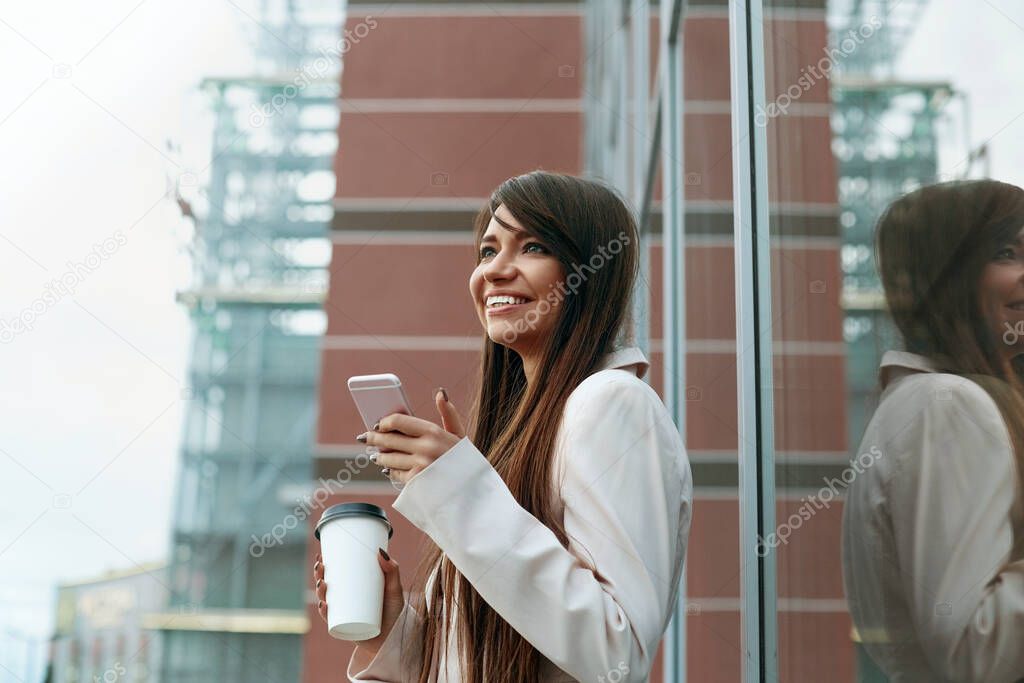 Businesswoman with coffee and talking on the phone near office