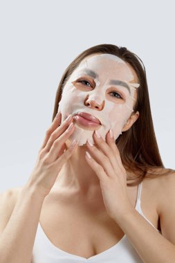 Güzellik Maskesi. Yüzüne nemlendirici maske takmış güzel bir genç kadın. Kozmetik spa maskesi. Yüz tedavisi
