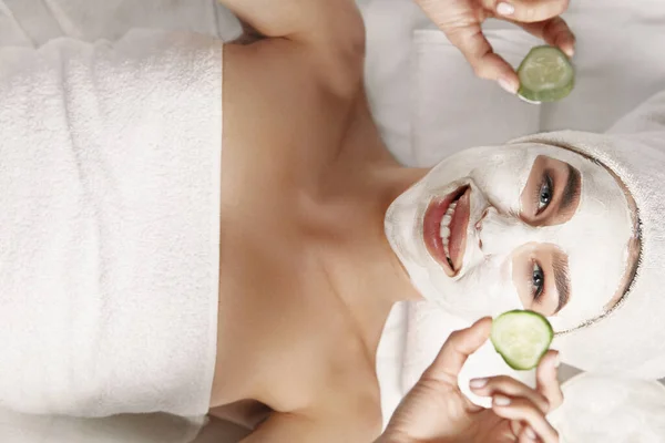 Mooie Jonge Vrouw Krijgt Gezichtsmasker Spa Liggend Met Komkommers Ogen — Stockfoto