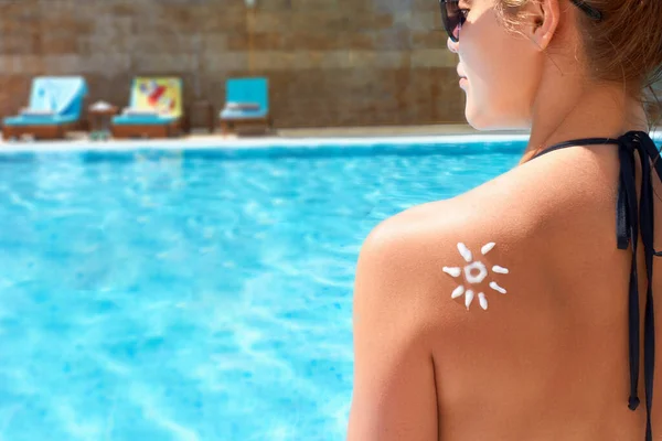 Woman Applying Sun Cream on Tanned  Shoulder In Form Of The Sun. Sun Protection.Sun Cream. Skin and Body Care. Girl Using Sunscreen to Skin.