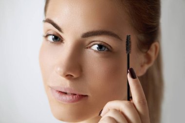 Kaşlarını düzelten genç ve güzel bir kadın. Kaş makyajı devam ediyor. . 