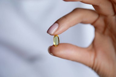 Kadın Ellerinin Morina yağlı Omega-3 ile hap almasına yakın çekim 
