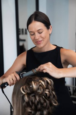 Yetenekli bir kuaför, odayı doğal ışık doldururken çağdaş bir kuaför ortamında bir müşteri için güzel bir yenilik yaratıyor..
