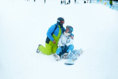 Kar kayağı yapmaya ara verip kış sporlarının tadını çıkaran iki kişi bir kayak merkezinde karlı bir anı paylaşıyor..