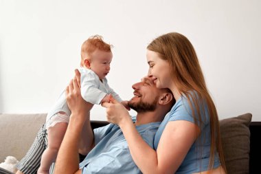 Ebeveynlerin bebekleriyle etkileşim kurduğu, sıcak bir oturma odasında kahkaha ve sevgiyi paylaştığı, sıcak bir aile bağını güçlendirdiği aile anları.