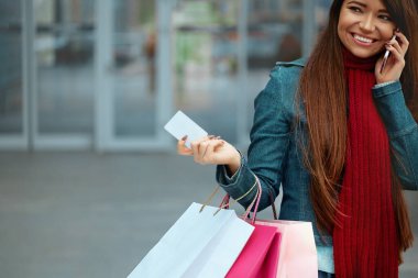 Alışveriş çantalı genç bir kadın. Olumlu duygular. Yaşam tarzı konsepti. Elinde Credt kartıyla gülümseyen genç ve güzel bir kadın.