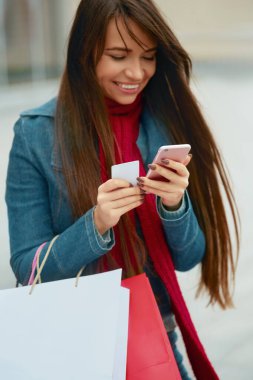 Cep Telefonu Kullanan Neşeli Kız Kredi Kartı Tutuyor. Alışveriş çantalı mutlu güzel kadın.