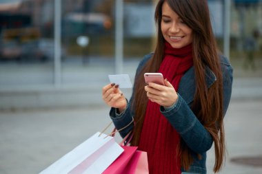 Cep Telefonu Kullanan Neşeli Kız Kredi Kartı Tutuyor. Alışveriş çantalı mutlu güzel kadın..