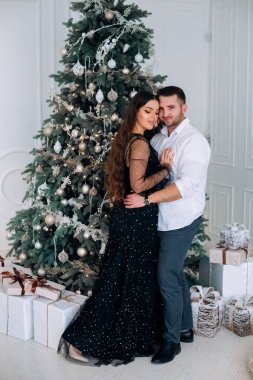 Güzel dekore edilmiş bir Noel ağacının önünde gülümseyen bir çift..