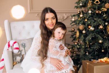 Bir anne ve küçük kızı karşılama odasında rahat beyaz bir sandalyeye otururlar..