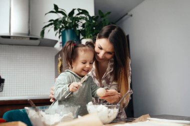 Bir anne ve kızı mutfakta özel bir şeyler pişirmek için çalışıyorlar. Birlikte yemek hazırlarken malzemeleri karıştırıp keyifli anları paylaşıyorlar..