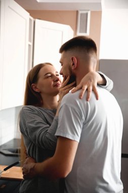 Bir çift, bir mutfakta birbirine sarılıp gözlerinin içine bakar. Bu özel anı evlerinde paylaştıkça sıcak bir bağları oluyor..