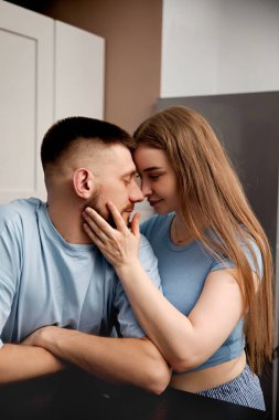 İki insan birbirine yakın durup evdeki mutfaklarında bir an paylaşıyorlar. Birbirlerine nazikçe gülümserler, öğleden sonra samimi bir bağ kurarlar..