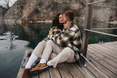 Sevgililer Günü 'nde, bir erkek ve bir kadın bir rıhtımda otururken bir aşk öpücüğü paylaşırlar..