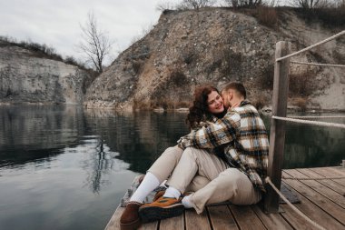 İki kişi sakin bir gölün kıyısındaki rıhtımda yan yana oturur. Doğadaki Sevgililer Günü 'nü kutlarken birbirlerine gülümserler..