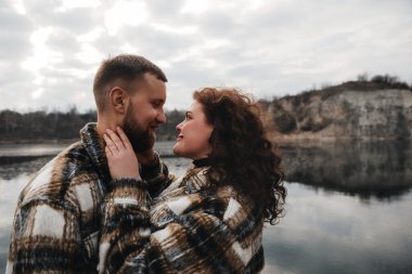 Sevgililer Günü 'nde iki kişi su kenarında yan yana durur. Gülümsüyorlar ve birbirlerinin gözlerine bakıyorlar..