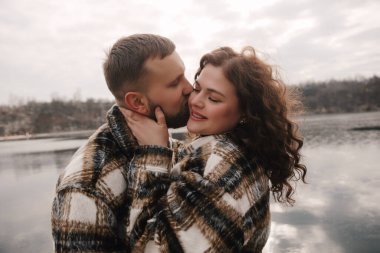 Bulutlu bir günde, iki insan birbirine sarılır, doğada bir sevgi ve bağ anlarını paylaşırlar..