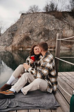 İki insan rıhtımda yan yana oturur, ellerinde fincanlar ve bir anı paylaşırlar. Kış öğleden sonra doğa tarafından kuşatılmışken..