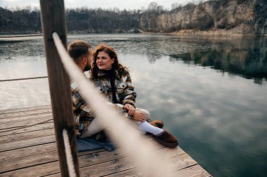 Sevgililer Günü 'nde tahta bir rıhtımda iki kişi romantik bir anı paylaşıyor. Birbirlerine odaklanmışlar..