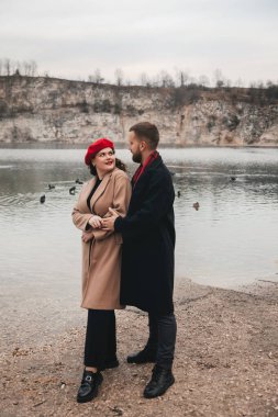 Sevgililer Günü 'nde bir kadın ve bir erkek birlikte suyun kenarında dururlar. Doğada geçirdikleri zamanın tadını çıkarırken aynı gülüşü paylaşıyorlar..