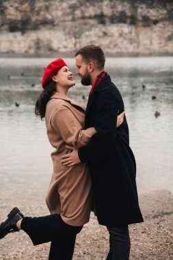 İki insan Sevgililer Günü 'nü deniz kenarında kutlar. Romantik bir ortamda birbirlerine eşlik ederken gülümser ve kucaklaşırlar..