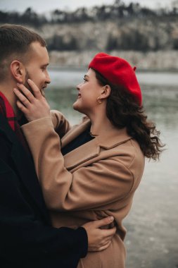 Sevgililer Günü 'nde iki kişi suyun kenarında keyifli bir anı paylaşıyor. Birbirlerine yakınlar, gülüyorlar ve mutlular, doğal bir ortamda..