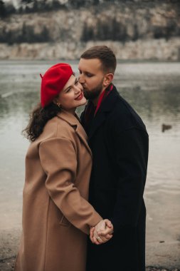 Sevgililer Günü 'nde iki insan gülümser ve bir su kütlesinin yanında el ele tutuşur. Romantik anlarında birbirlerine sevgi ve yakınlık gösterirler..