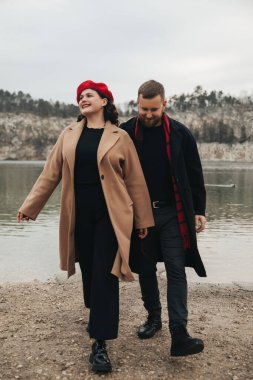 İki insan, bir adam ve bir kadın, bulutlu bir günde sıcak giysiler içinde göle doğru yürür ve birbirlerine bağlanırlar..