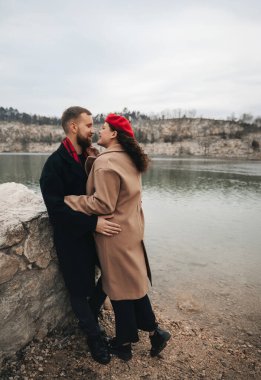 Sevgililer Günü 'nde kışın iki kişi su kenarında bir anı paylaşır. Kayalık bir kıyı şeridinde dururken kucaklaşıyorlar..