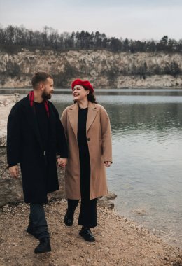 İki insan sakin bir gölün kıyısında yürürler kalın paltolar giyerek ve güzel bir Sevgililer Günü 'nde birbirlerine gülümseyerek..
