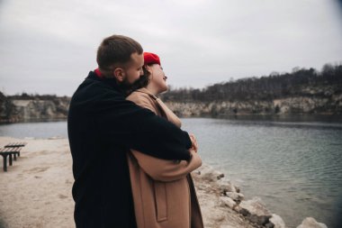 Bir erkek ve kadın göl kenarında sıcak bir anı paylaşıyor Sevgililer Günü 'nün tadını çıkarıyor ve birlikte aşklarını kutluyorlar..