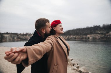 Birkaçı suyun kenarında el ele tutuşuyor. Bulutlu bir günde birbirlerine eşlik ederken gülümserler ve yakın bir anı paylaşırlar..