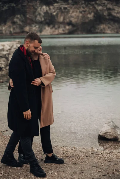 Sevgililer Günü 'nde açık havada eğlenirken gülümseyen ve kucaklayan iki insan bir su kütlesinin yanında bir anı paylaşır..