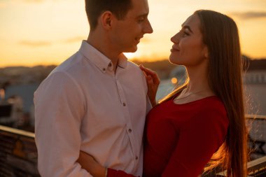 Gün batımında bir erkek ve bir kadın çatıda birbirlerine yakın dururlar. Güneş arkalarında batarken birbirlerine gülümserler..