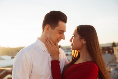 İki insan çatıya yakın durur, gün batımının tadını çıkarırken birbirlerinin gözlerinin içine bakar ve birlikte güzel bir anı paylaşırlar..