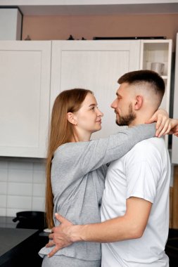 İki insan bir mutfakta birbirine yakınlaşır ve bir anı paylaşır. Mutfak dolapları ve ev eşyalarıyla çevriliyken birbirlerine bakarlar..