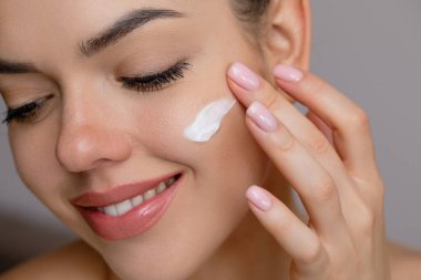 Cilt bakımı. Güzel yüzlü kadın sağlıklı yüz portresine dokunuyor. Güzel bir kız model krem sürmeye başladı.