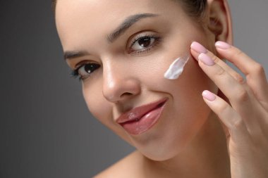 Güzel yüzlü bir kadın sağlıklı yüz portresine dokunuyor. Güzellik güzeli kız cilt bakımı ürünü uyguluyor. Sıvı kaybı. Krema lekesi.