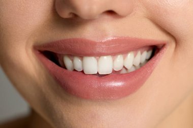 Bir kadın gülümser ve sağlıklı tenini makyajlı bir şekilde kaplıcada cilt bakımında gösterir..