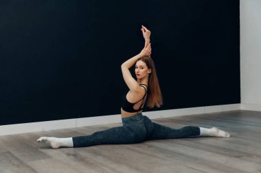 Genç bir kadın spor salonunda esneme egzersizi yapıyor. Uygun tekniği kullanarak spor salonuna ve sağlığa odaklanıyor..