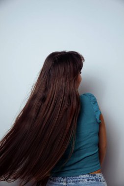 Tarafsız arka planda izole edilmiş genç bir kadının yan görünüm portresi.