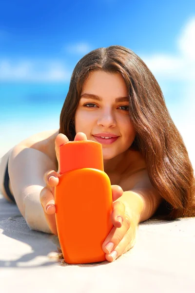 Portrait of gorgeous young woman  while relaxing on beach and holding sunscreen bottle — Stock Photo, Image