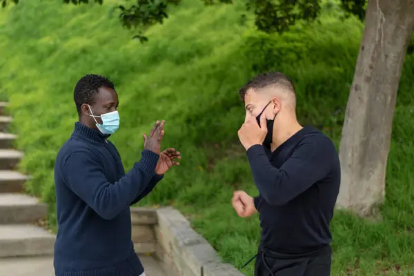 Siyah adam ve beyaz adam parkta egzersiz yapıyor.