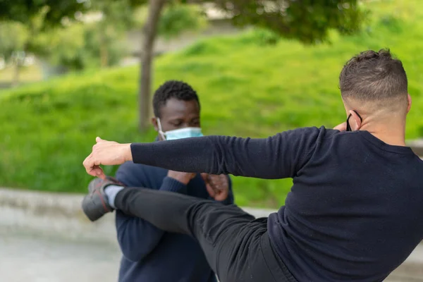 Siyah adam ve beyaz adam parkta tekmeliyor.