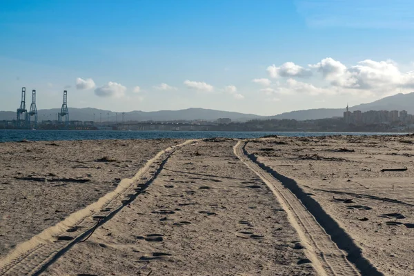 Arka planda algeciras limanı olan kumsaldaki lastik izleri.