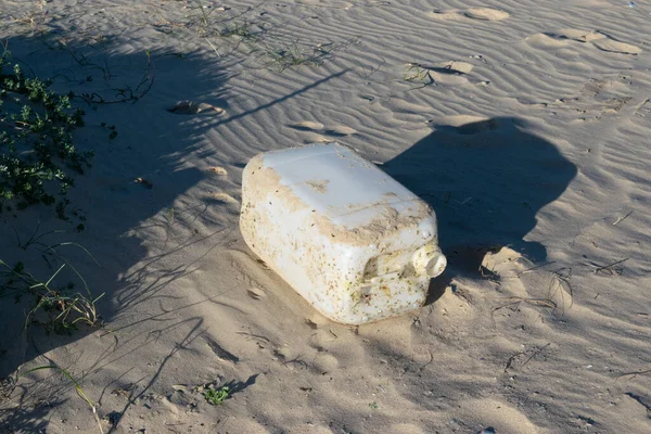 Sahilde dalgalarla yıkanan büyük bir plastik şişe.