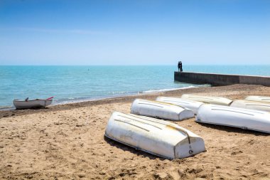 Michigan Gölü 'nün kumlu sahilinde kayıklar. Beton bir iskelede göle bakan bir çift..
