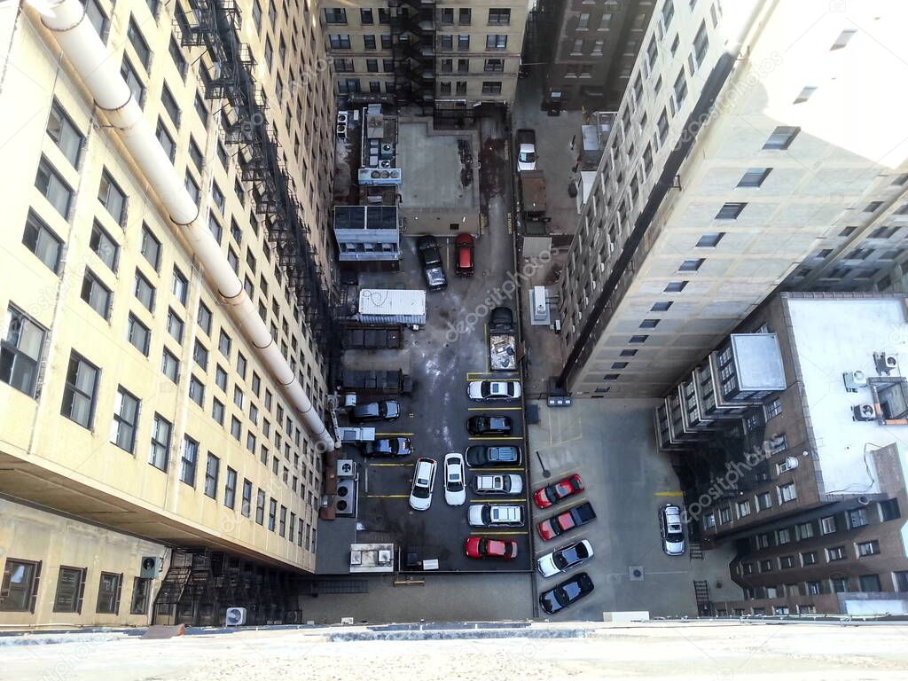 Dizzying view looking down from the rooftop of a high-rise apartment building to the couryard like alleyway below