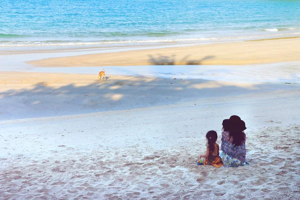 Mother and daughter sitting at the beach on hoiday — Stock Photo, Image