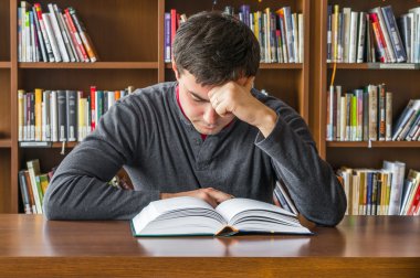 Genç adam ahşap bir masa üzerine bir kitap okuma
